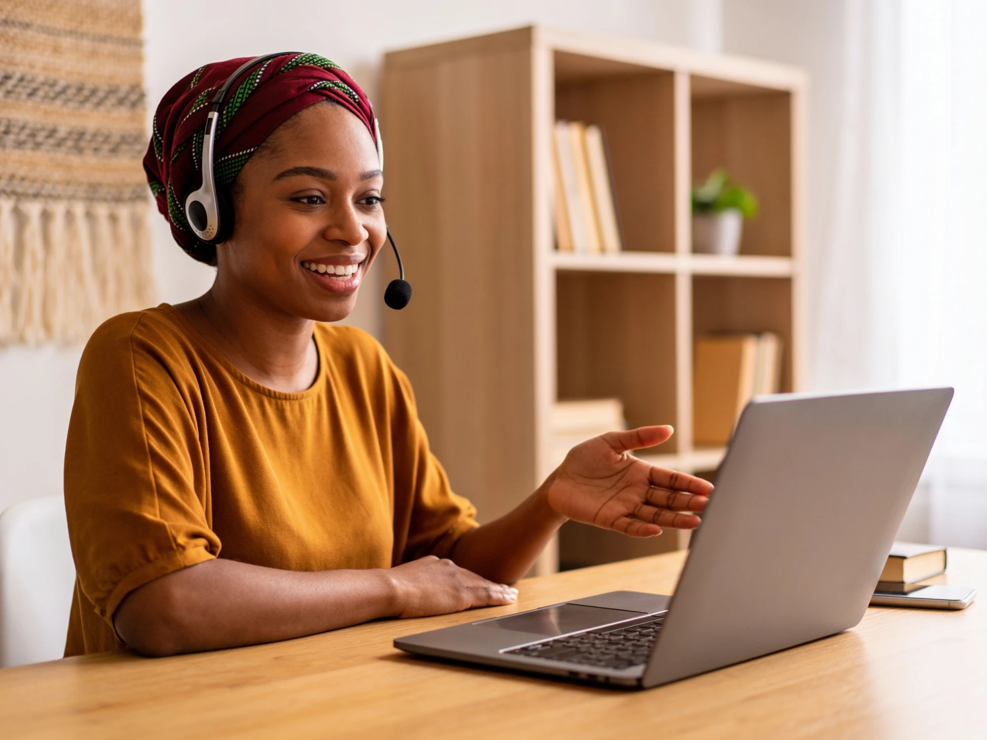 A smiling tutor with a headset leads a live online lesson from her laptop